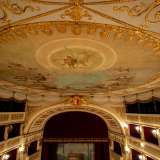 Risalendo ancora verso il soffitto, l�occhio � rapito dal ricco velario bianco a frange e nappe d�oro, decorato con bassorilievi dorati a festoni, nastri, palmette e trionfi musicali